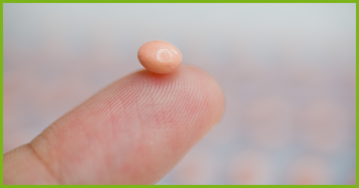 progesterone pill balanced on fingertip